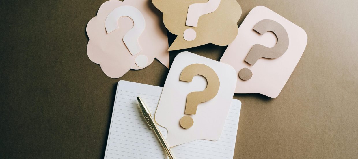 Flat lay of question mark paper crafts on a notebook, symbolizing questions and ideas.